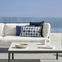 Stylish white sofa with blue and patterned throw pillows; elegant coastal decor with clean lines.