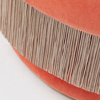 Coral velvet cushion with beige fringed trim, featuring a soft, textured pattern for a stylish accent.