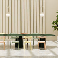 Elegant green dining table surrounded by pastel-colored chairs: pink, yellow, and light green, set against a soft beige backdrop.