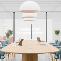 "Modern conference room featuring a light wood table, pastel green and pink chairs, and white pendant lights."