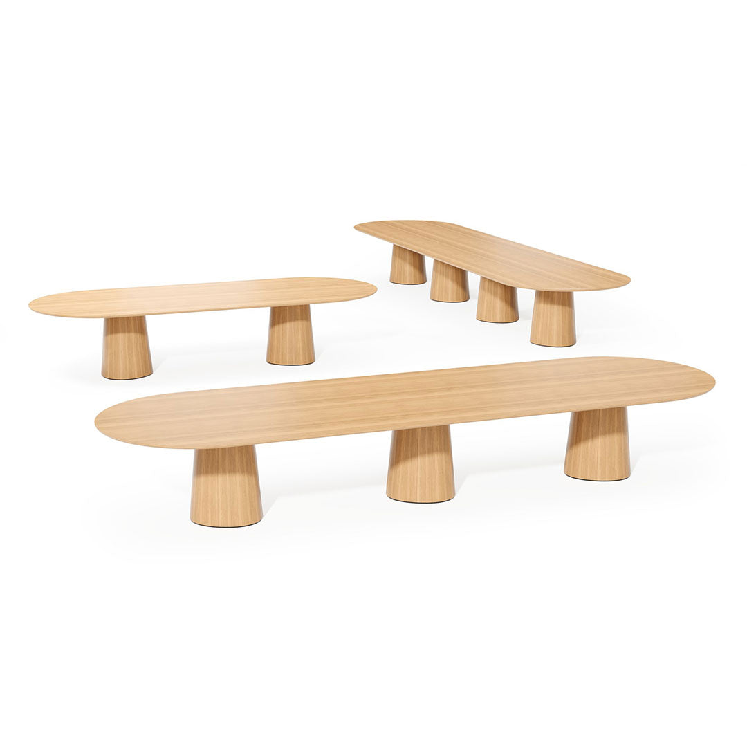 Set of three minimalist wooden tables in light oak finish, featuring smooth oval tops and cylindrical bases.