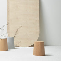 Wooden and metallic stools in natural tones, featuring soft curves and a minimalist aesthetic against a light background.