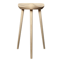 Natural wood stool with a light finish and smooth, minimalist design, featuring tapered legs and a softly curved seat.