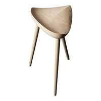 Light natural wood stool with a smooth, curved seat and tapered legs, showcasing a minimalist design and neutral tones.