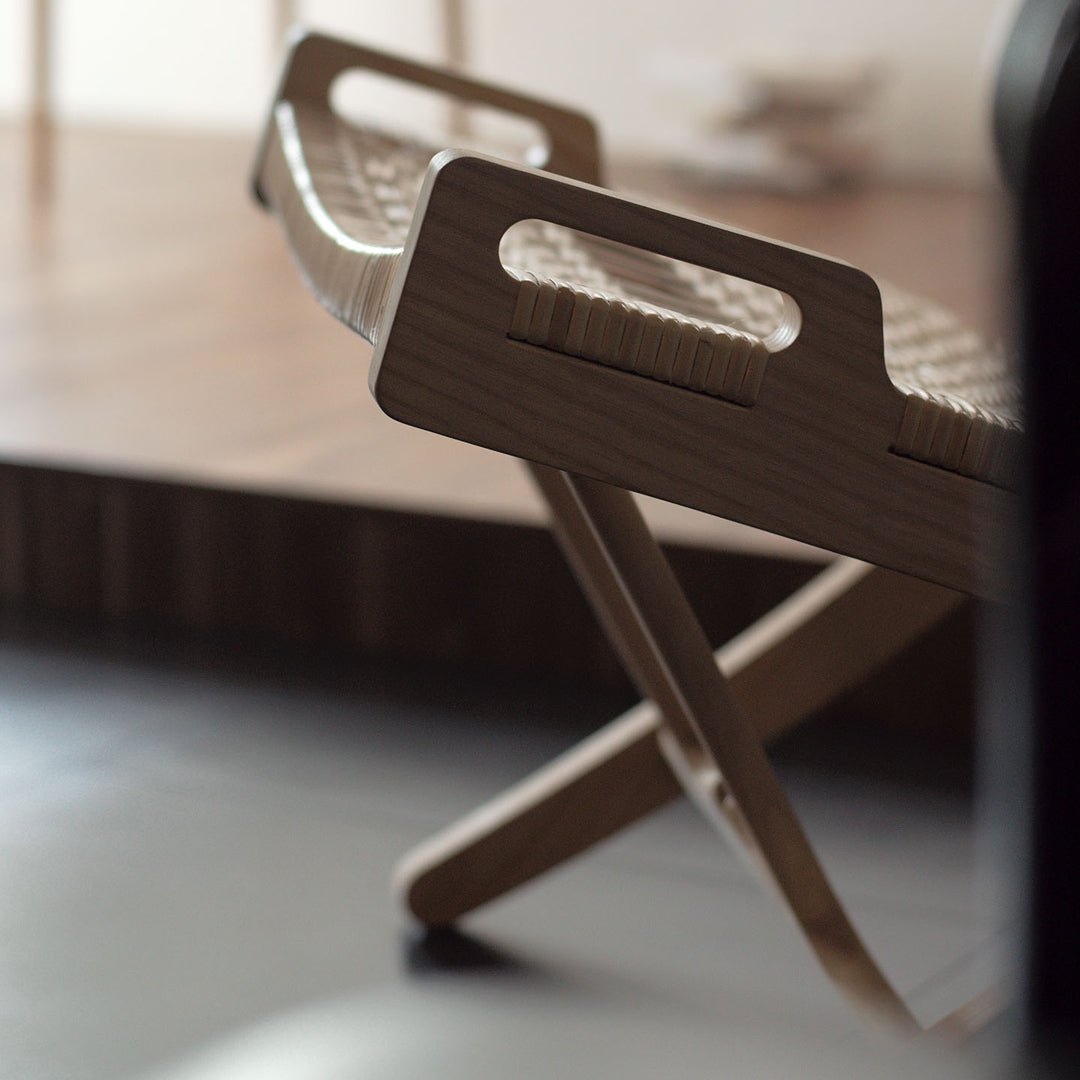 Natural wood folding chair featuring woven pattern and light tones, perfect for modern indoor spaces.