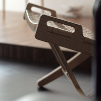 Natural wood folding chair featuring woven pattern and light tones, perfect for modern indoor spaces.