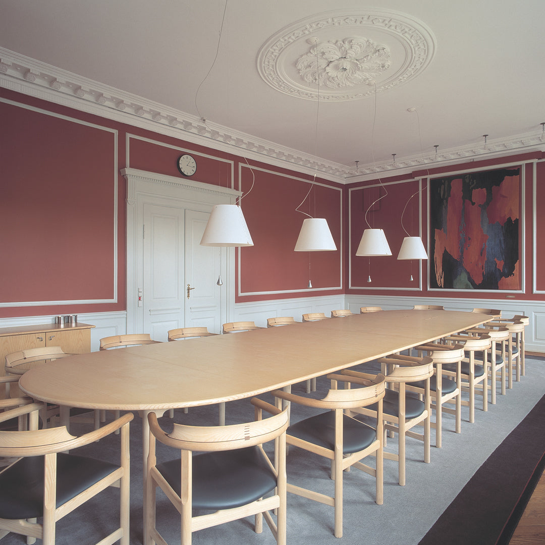 Elegant pink walls, white chandeliers, and a light wood table pair with dark grey flooring for a modern look.