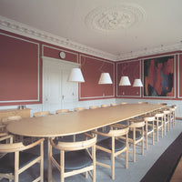 Elegant pink walls, white chandeliers, and a light wood table pair with dark grey flooring for a modern look.