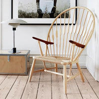Natural wood chair with a light finish, featuring a unique spoked back and dark wood armrests, complementing a modern interior.