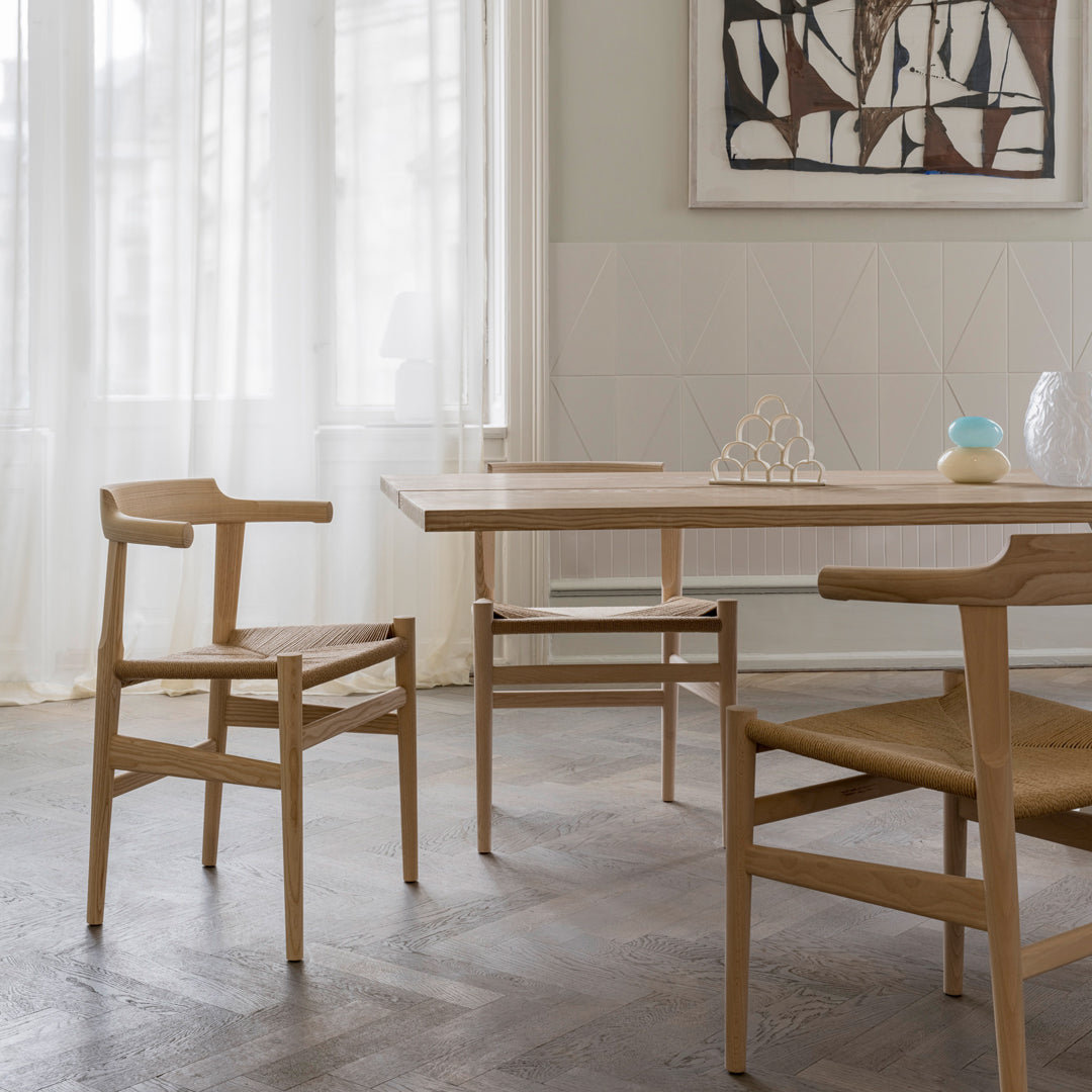 Light wood dining table and chairs with natural finish, complemented by neutral walls and soft, textured fabrics.