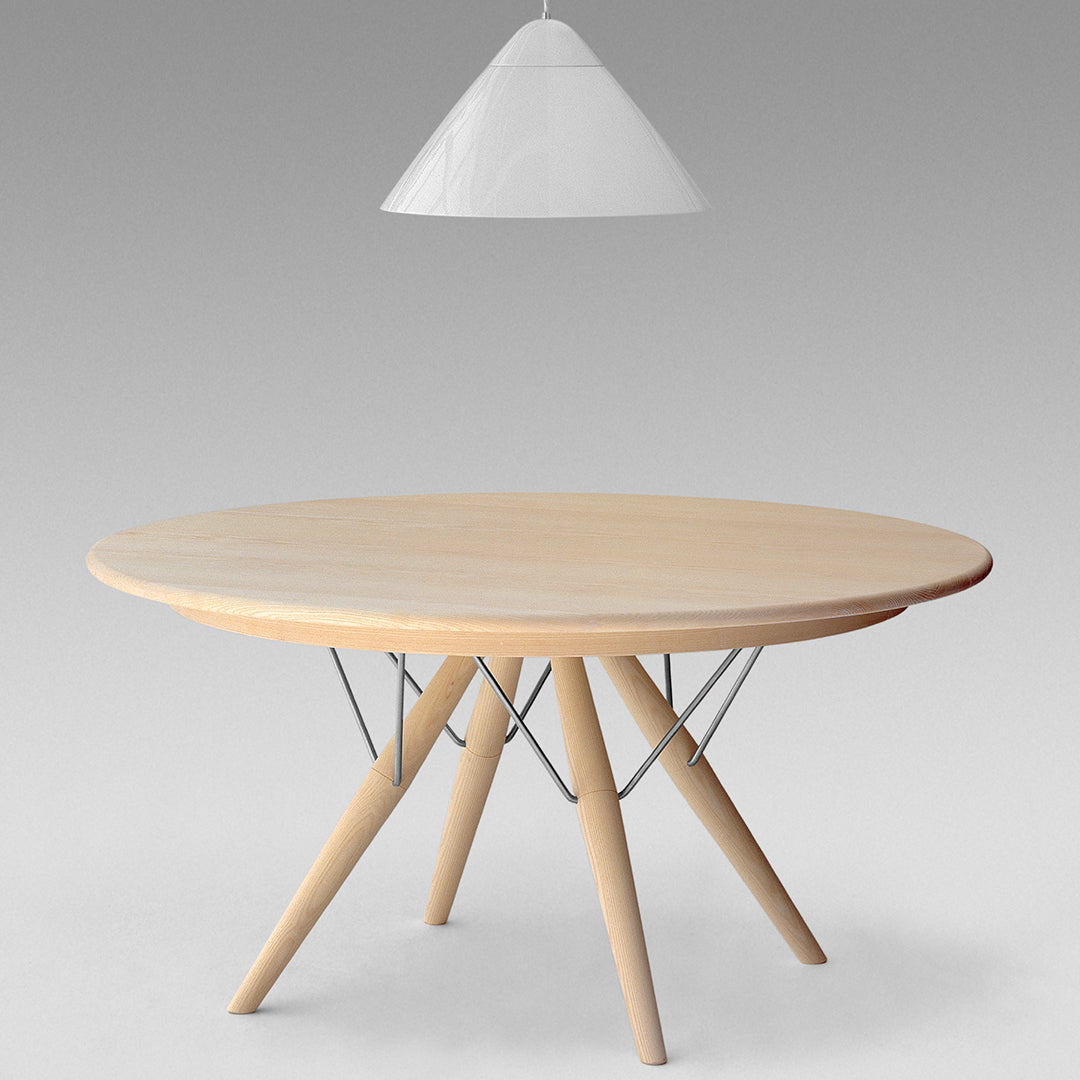 Light wood round table with minimalist metal legs, featuring a natural finish and smooth surface. Hanging white pendant light.