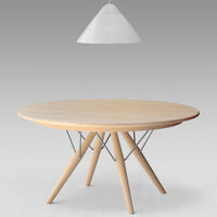 Light wood round table with minimalist metal legs, featuring a natural finish and smooth surface. Hanging white pendant light.