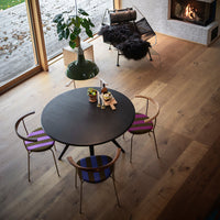 Round black table with purple and blue striped chairs in a modern living space with wooden flooring.
