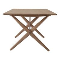 Light brown wooden table with a simple, clean design and crossed legs, perfect for modern dining or decor.