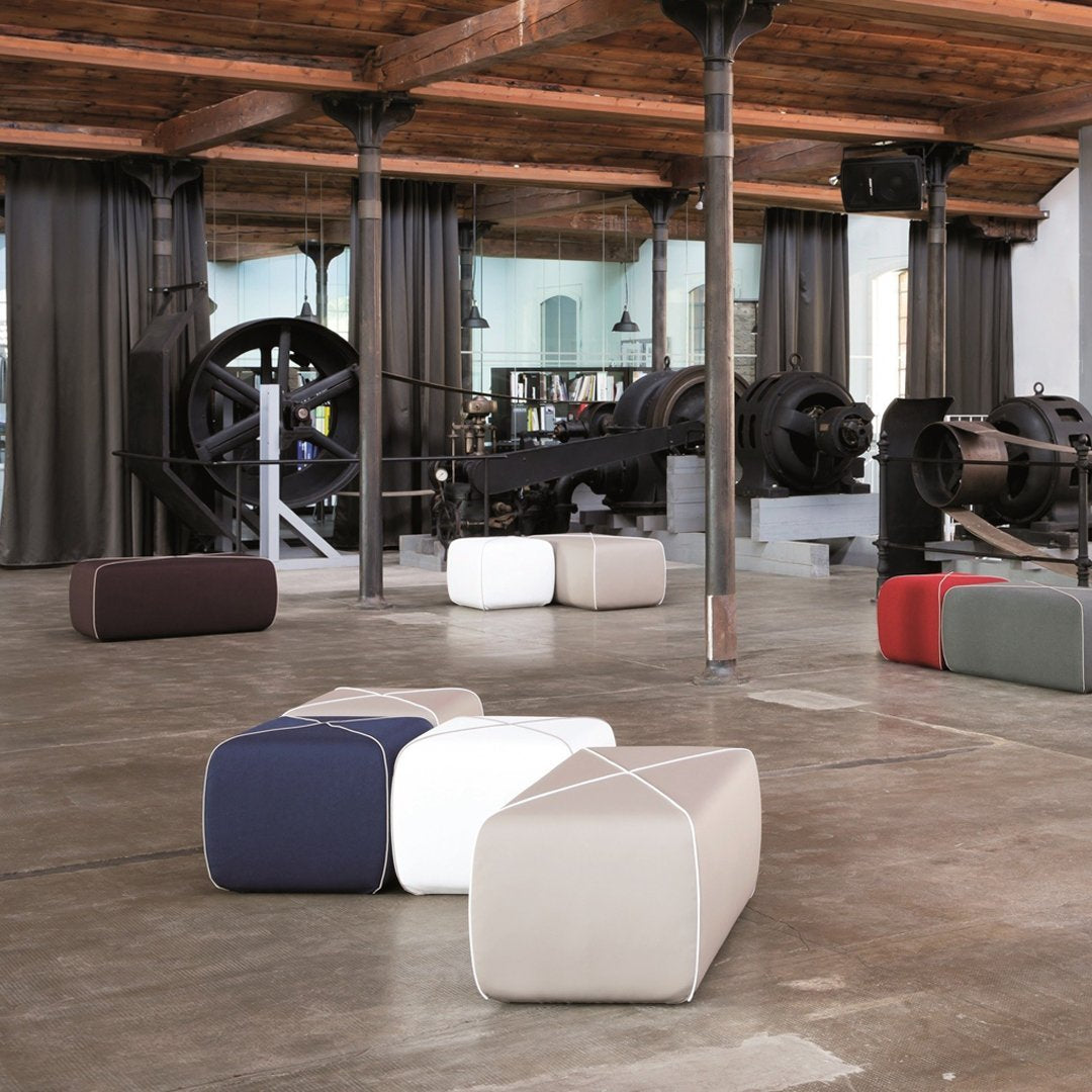 Colorful ottomans in navy blue, white, light gray, and red, featuring a sleek, modern design and smooth textures.