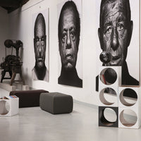 Modern art display featuring black and white portraits with sleek, geometric white furniture in a minimalist setting.