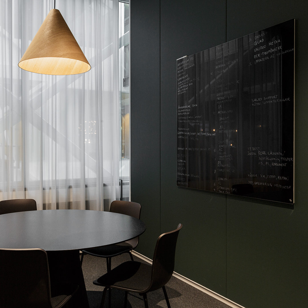 Black glass wall art with abstract patterns on a dark green wall, surrounded by a minimalist dining setup.