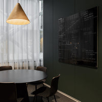 Black glass wall art with abstract patterns on a dark green wall, surrounded by a minimalist dining setup.
