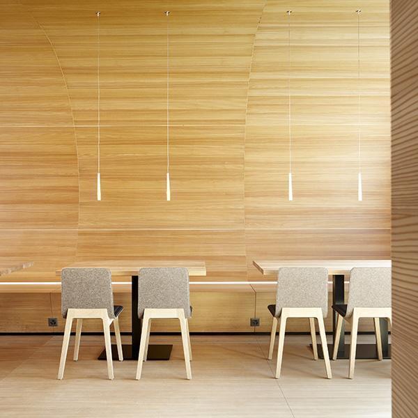 Neutral-toned chairs with light wooden legs against a textured wood panel backdrop. Minimalist design and natural colors.