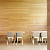 Neutral-toned chairs with light wooden legs against a textured wood panel backdrop. Minimalist design and natural colors.