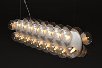 Hanging lamp with clear glass globes and a sleek white base, featuring a modern minimalist design.