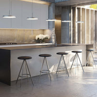 Modern kitchen featuring sleek white cabinetry, gray concrete accents, and black bar stools with metal frames.