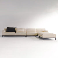 Beige sectional sofa with black accent pillow, featuring a sleek, modern design and minimalist style.
