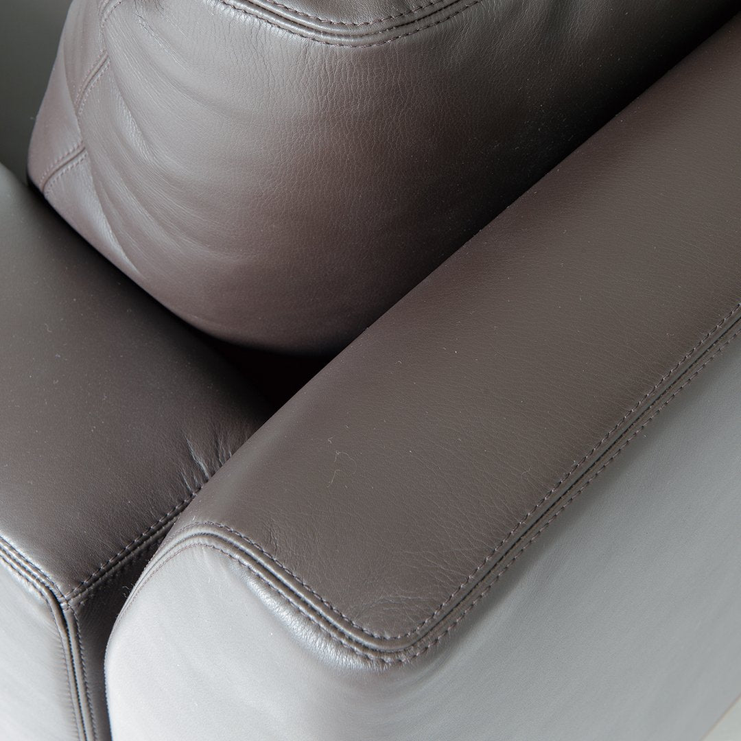Close-up of dark brown leather sofa cushions with smooth texture and subtle stitching detail.