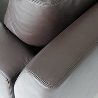 Close-up of dark brown leather sofa cushions with smooth texture and subtle stitching detail.