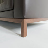 Brown leather sofa with a sleek wooden base and clean, modern lines, showcasing an elegant, minimalist design.