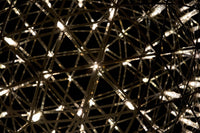 Intricate geometric pattern of gold and silver lines, illuminated against a dark background, creating a luminous effect.