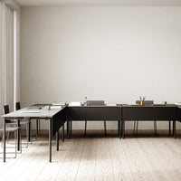Modern black tables with sleek lines and minimalistic design, set against light wooden floors and soft neutral walls.