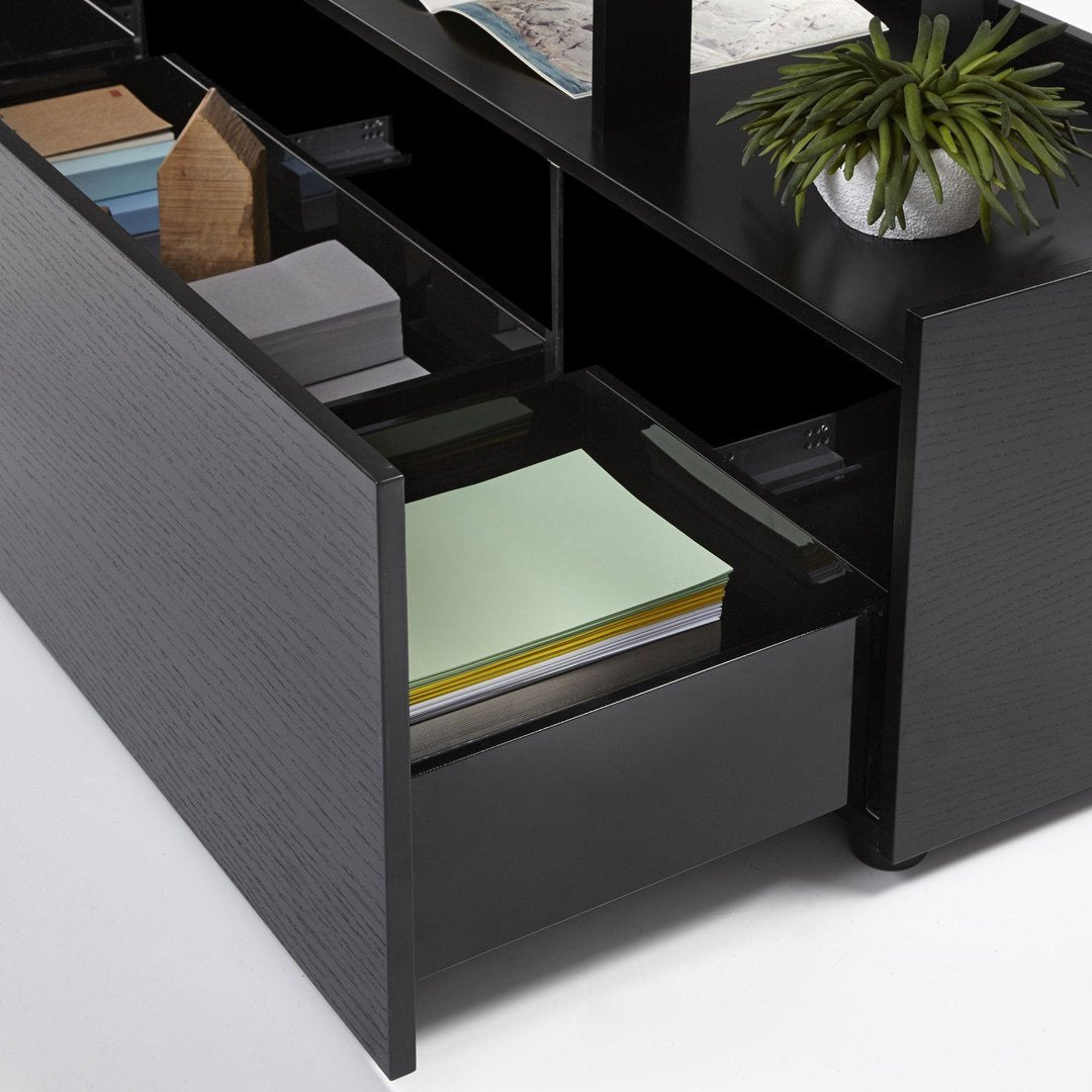 Black wooden drawer with light green, blue, and gray paper arranged neatly inside, showcasing a modern, minimalistic design.