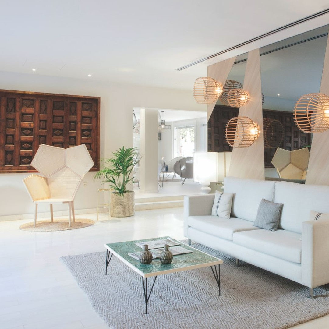 "Modern living room featuring neutral tones, wicker light fixtures, and a patterned rug with green accents."