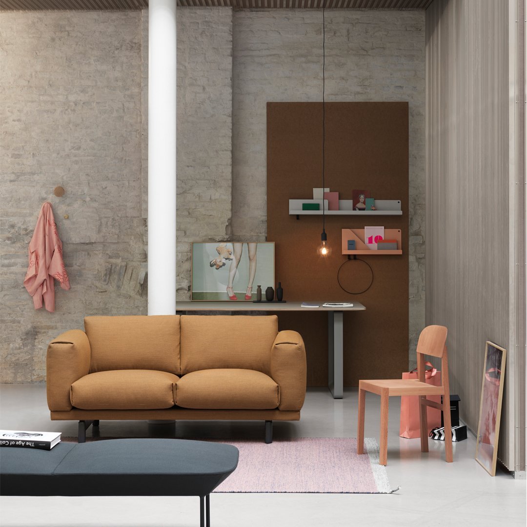 Stylish brown sofa with soft cushions, paired with pastel pink and beige accents in a modern, minimalist setting.