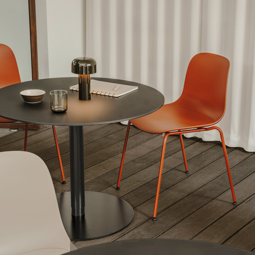 Terracotta chairs with sleek black table on wooden flooring, complemented by light-colored decorative elements.