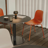 Terracotta chairs with sleek black table on wooden flooring, complemented by light-colored decorative elements.