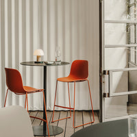 "Modern orange bar stools and sleek black table against soft white backdrop, creating a stylish and contemporary setting."