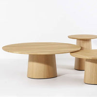 Natural oak wood coffee tables with smooth round surfaces and simple cylindrical bases. Light wood tones and minimalist design.