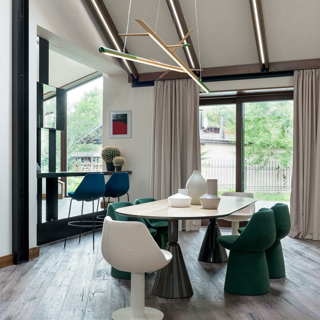 Modern dining set featuring white, green, and blue chairs with a wooden table, set in a bright, stylish interior.