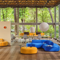 Bright blue and yellow seating with circular patterns in a modern office space, surrounded by greenery.