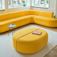 Bright yellow sectional sofa with smooth curves and a matching round coffee table on a light-colored area rug.