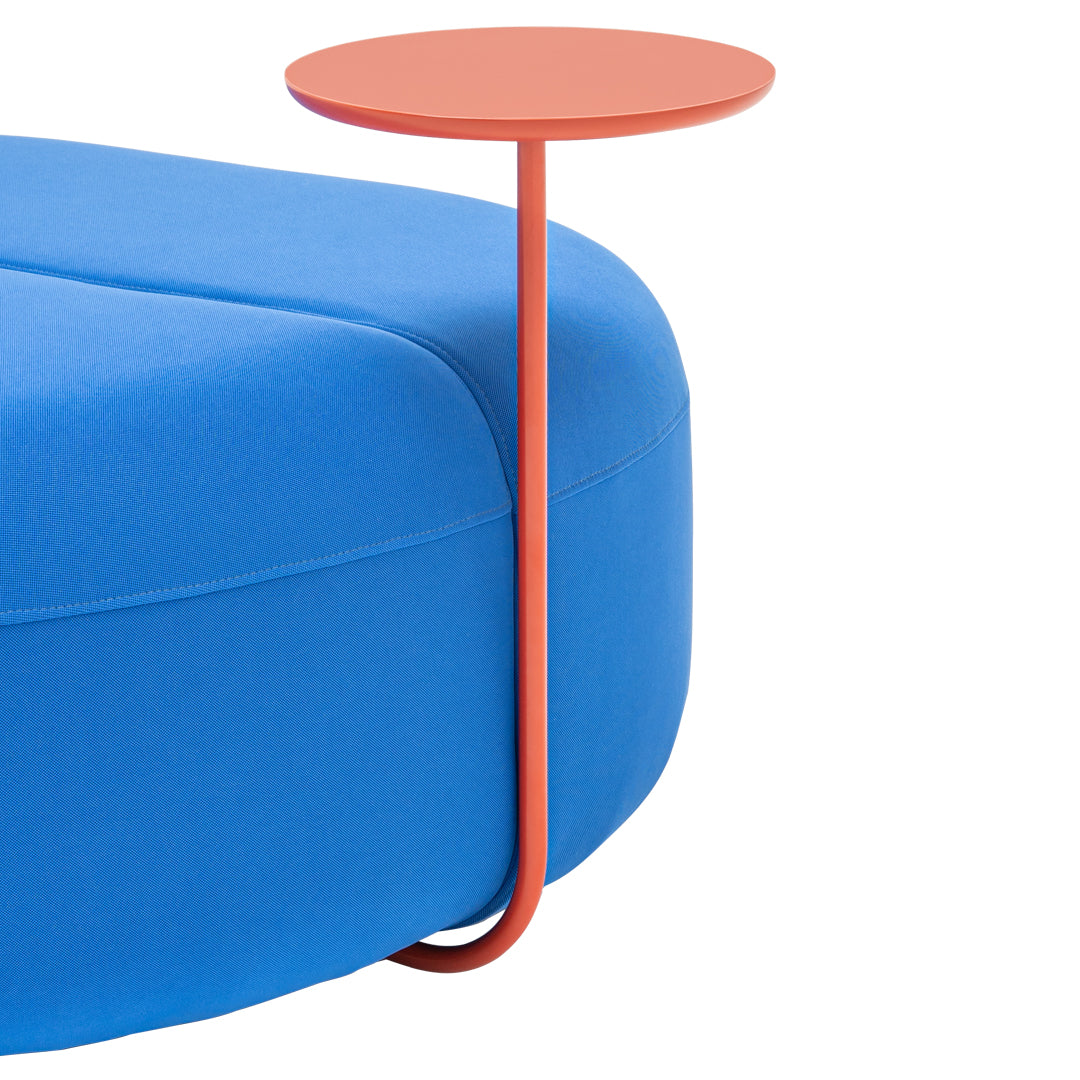 Bright blue cushion with a sleek, coral accent table. Modern, minimalist design showcasing vibrant color contrast.