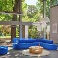 Modern living room featuring vibrant blue curved sofa, light wood table, and soft organic shapes in a bright, airy space.
