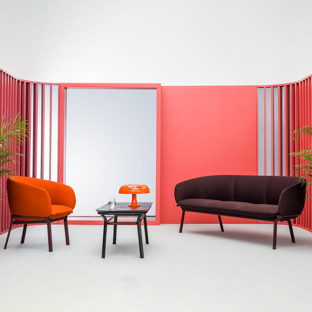 Modern living space featuring bold orange and deep burgundy seating against a vibrant pink backdrop. Stylish and eye-catching.