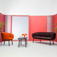 Modern living space featuring bold orange and deep burgundy seating against a vibrant pink backdrop. Stylish and eye-catching.