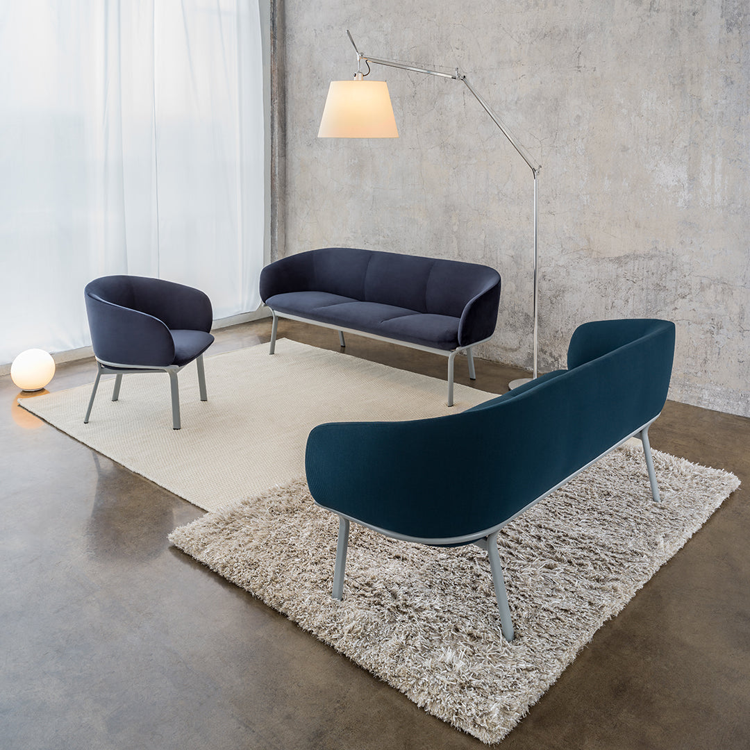 Modern sofa set featuring navy blue and teal upholstery on sleek gray legs, complemented by a textured beige rug.