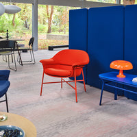 Bold orange chair, vibrant blue partition, and modern decor on light patterned flooring create a stylish indoor space.