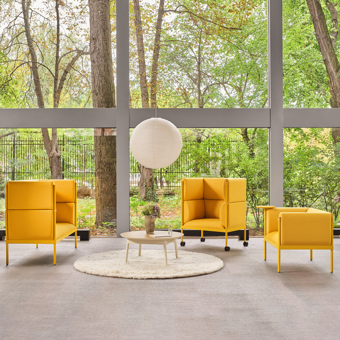 Bright yellow chairs and a round white rug create a cheerful, modern seating area surrounded by greenery.