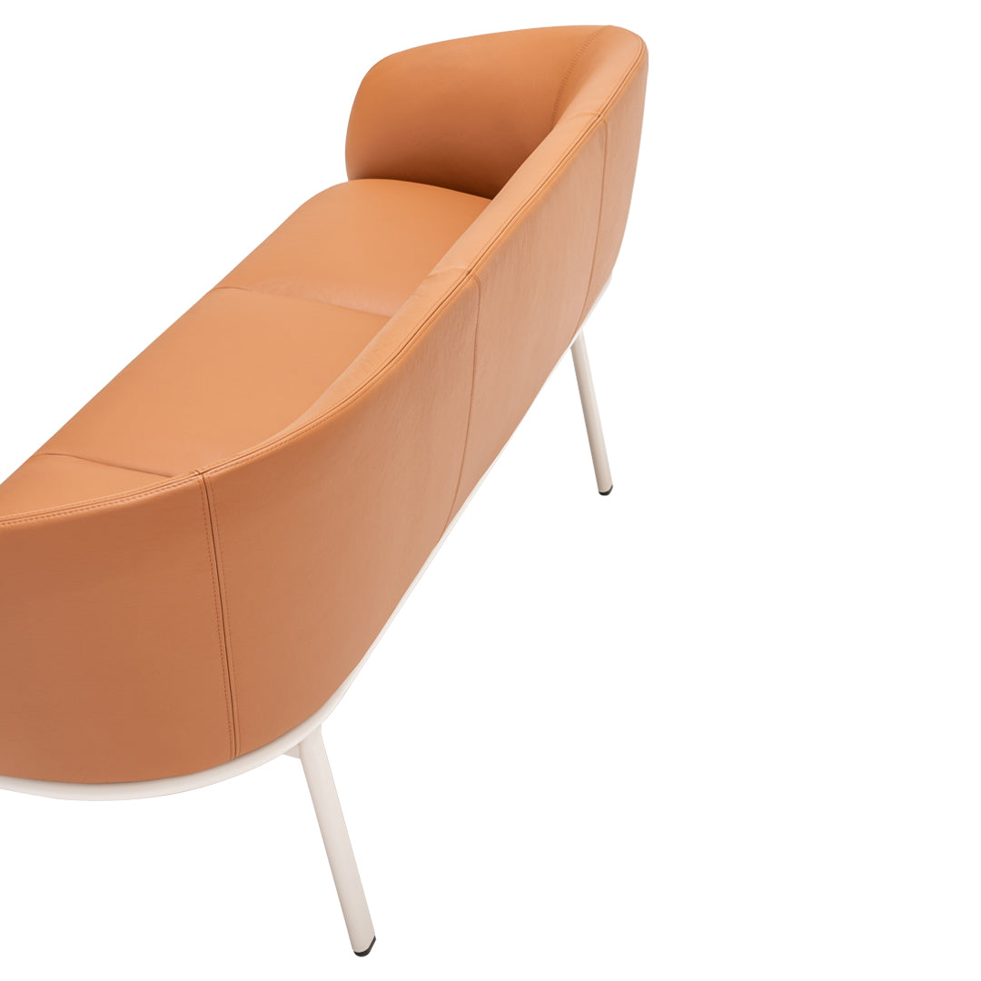 Stylish curved sofa in warm tan leather with sleek white legs, perfect for modern interiors.